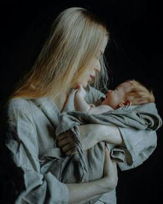 a woman holding a baby wrapped in a blanket