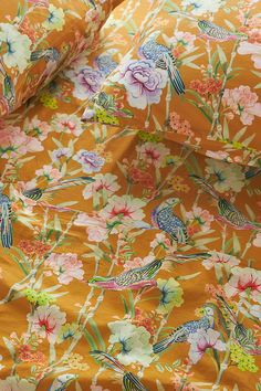 an orange floral fabric with birds and flowers all over it on top of each other