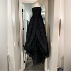 a black dress hanging on a hanger in a hallway next to an open door