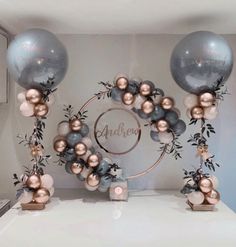 two balloons and some decorations on a table with silver, pink and gold balls in the middle