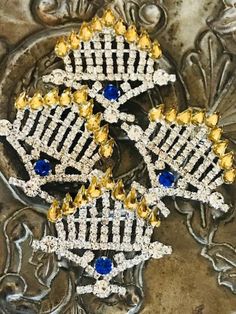 three brooches with blue and yellow stones on them