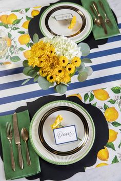 a table set with place cards, silverware and yellow flowers