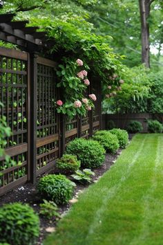 a lush green yard with lots of trees and flowers on the fenced in area