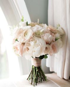 a bouquet of flowers sitting on top of a window sill next to a curtain