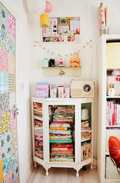 a white cabinet filled with lots of different types of fabrics and quilts on top of it