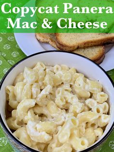 there is a bowl of macaroni and cheese on the table with bread next to it