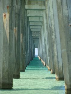 the underside of a long pier with water underneath it and one person walking on the dock