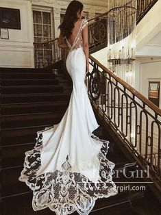 a woman in a white wedding dress standing on stairs with her back to the camera