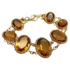 What makes this Victorian 14k gold bracelet so beautiful are the magnificent, well-matched amber hued citrine gemstones that have stunning presence on the wrist. The stones graduate in size with the largest stone as the centerpiece, measuring 22 x 16 x 10.5 mm. The presentation is rich, warm facets of citrines that dominate the overall look of the bracelet. The stones are bezel set into gold that is crimped around the edges, framed by Etruscan Revival wirework. The gemstones are held together by Timeless Citrine Gemstone Jewelry, Luxury Amber Jewelry For Formal Occasions, Classic Citrine Jewelry With Gemstone Accents, Elegant Citrine Gemstones With Gemstone Accents, Timeless Citrine Jewelry For Formal Occasions, Elegant Citrine Jewelry In Amber, Luxury Hallmarked Citrine Jewelry, Luxury Oval Citrine Jewelry, Elegant Oval Amber Gemstones