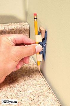 a person holding a pencil and eraser in front of a wall with an eraser attached to it