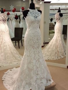 a white wedding dress on display in front of a mirror with other dresses behind it