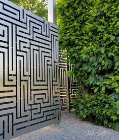 an outdoor sculpture made out of metal and surrounded by greenery on the side of a building