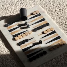 a white board with black and gold buttons on it sitting on the floor next to a roll of toilet paper