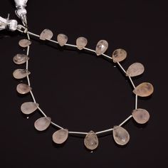 a necklace made out of glass beads and silver wire on a black surface with a white bea