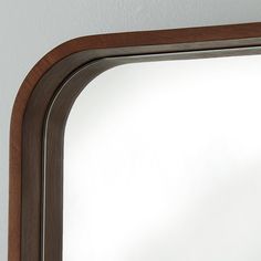 a mirror that is on the wall with a wooden frame and wood trim around it