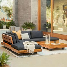 a living room with a couch, coffee table and potted plants