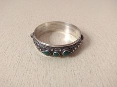 This is a beautiful silver bracelet from Morocco with a very original design, It is embellished with a small natural malachite beads ,It is a bracelet in the hand and very well worked. Inner Diameter : 6 cm (2,4 inches) Width : 1,8 cm (0,7 inches) Weight : 49,6 g Artisan Green Bangle Bracelet, Green Sterling Silver Bracelets With Silver Beads, Green Sterling Silver Bracelet With Silver Beads, Bohemian Green Sterling Silver Bracelet Gift, Green Bohemian Sterling Silver Bracelet For Gift, Spiritual Malachite Bracelet Jewelry, Spiritual Green Bangle Cuff Bracelet, Bohemian Handmade Green Sterling Silver Bracelet, Handmade Bohemian Green Sterling Silver Bracelet