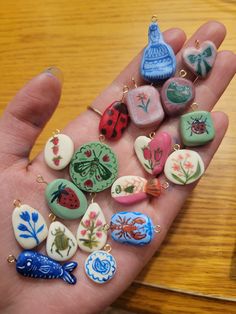 a person's hand holding several different colored buttons and charms on it, all in the shape of hearts