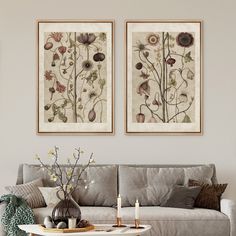 two paintings on the wall above a couch in a living room with candles and flowers