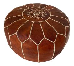 a brown leather ottoman with white stitching on the top and an embroidered design on the bottom