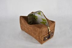 a brown bag with a zipper on the side and a green flower print lining it