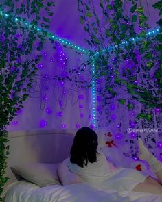 a woman laying in bed with purple lights on the ceiling and ivy growing over her head