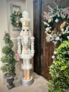 a large nutcracker statue sitting next to a potted plant in front of a door