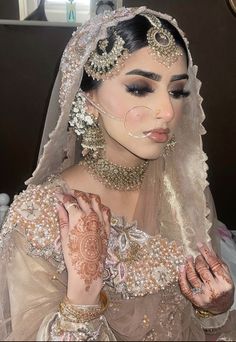 a woman in a bridal dress with makeup on her face and hands, wearing an elaborate head piece