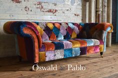 a multicolored couch sitting on top of a wooden floor next to a brick wall