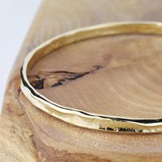 A beautiful solid 9ct gold bangle, textured with the signature Storybook finish both inside and out.The Storybook texture reflects the tactile quality of leather bound books from Alison's childhood and it is finished with a gorgeous flowing edge reminiscent of well thumbed pages of those books.The gold bangle gently flows around your wrist and its natural feel and simple style make the bangle the perfect piece of jewellery.. A lovely, unique design which will be cherished for years to come.Each Hammered Yellow Gold Bangle Bracelet, Gold Hand Forged Bracelets For Anniversary, Adjustable Hammered Yellow Gold Bracelet, Anniversary Hammered Yellow Gold Bracelets, Hammered Yellow Gold Bangle For Everyday, Everyday Hammered Yellow Gold Bangle, Hammered Gold Bracelet Gift, Hammered 14k Gold Bracelet For Gift, Hammered Yellow Gold Plated Bracelets