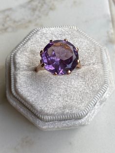 A huge 6 carat amethyst sits in a basket setting of 18k rose gold. This ring is truly a show stopper! The amethyst is synthetic (meaning created in a lab rather than in nature) and sparkles with light purple and blue undertones.  Details: Metal Purity -18k yellow gold (professionally acid tested to confirm) Ring size - 7.5 Weight - 5.3g Amethyst size - 14 mm diameter, 6 carats Ring Rise off of finger - 7.64 mm If this isn't your size, you are welcome to have it sized on your own, OR we can have it sized for a modest cost (just message us, and we will make it happen!). Layaway available. Please see shop policies for details. https://www.etsy.com/shop/TheTallestPoppy#policies About our vintage jewelry: Our jewelry is 100% crafted with vintage materials, as we try to retain as much of the ori Timeless Purple Amethyst Ring, Luxury Solitaire Amethyst Ring As Gift, Fine Jewelry Rose Gold Round Amethyst Ring, Luxury Solitaire Amethyst Ring, Formal Rose Gold Amethyst Ring In 14k Gold, Elegant Rose Gold Solitaire Amethyst Ring, Formal Rose Gold Amethyst Ring, Rose Gold Amethyst Ring With Round Cut, Classic Rose Gold Amethyst Ring With Prong Setting