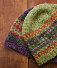 two knitted hats sitting on top of a wooden floor