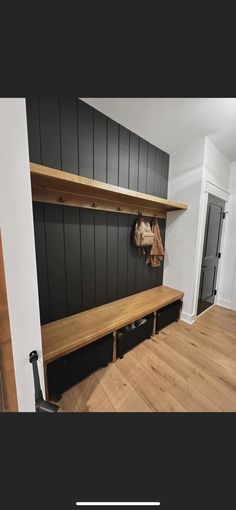 a wooden bench sitting in the middle of a room next to a wall mounted coat rack