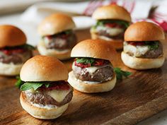 mini burgers with meat and cheese are arranged on a cutting board, ready to be eaten