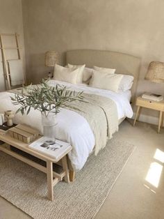 a large bed sitting next to a table with a potted plant on top of it