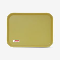 a yellow plastic tray on a white surface with a red sticker in the middle