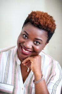 a woman with short hair smiling and looking at the camera while wearing a striped shirt