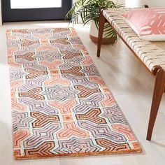 a colorful rug on the floor in front of a couch and table with potted plants