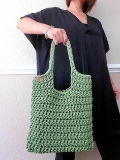 a woman holding a green crocheted bag