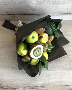 a bunch of fruit sitting in a black paper bag on top of a wooden table