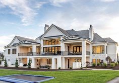 a large white house with a blue trampoline in the front yard and lawn