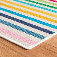 a multicolored rug is laying on the floor next to a wooden table top