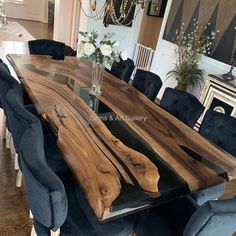 a dining room table made out of wood and black velvet chairs with flowers in vase