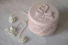 a white box sitting on top of a table next to pearls and roses with two hearts