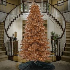 a christmas tree is in the middle of a room with stairs and a spiral staircase