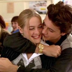 a man and woman hugging each other in a classroom