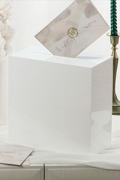 a white box sitting on top of a table next to a candle and some flowers