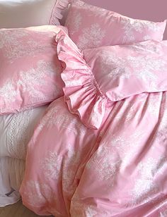 a bed with pink sheets and pillows on it