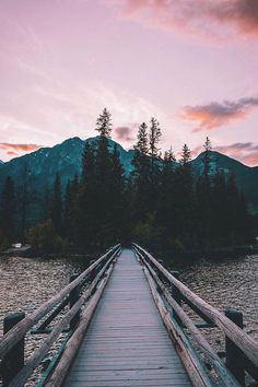 a wooden bridge over water with mountains in the background