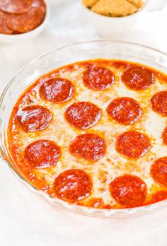 a pepperoni pizza sitting on top of a glass pan next to other food items